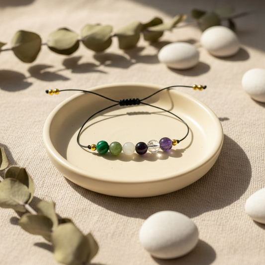 Necklace with multicolored beads on a beige plate surrounded by white eggs and green leaves.