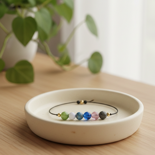 Beaded bracelet on a white ceramic dish with a plant in the background