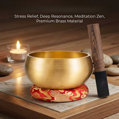 Brass singing bowl on a red silk brocade cushion with its mallets, styled beside lit candles