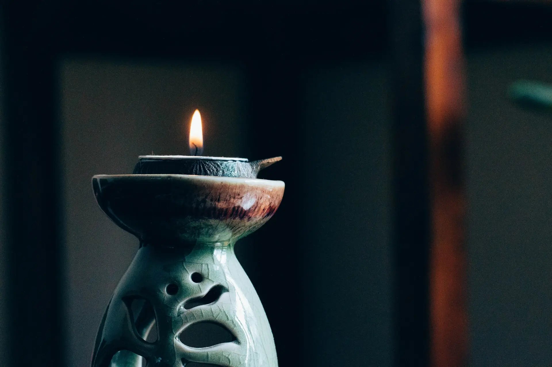 Ceramic oil lamp with a lit candle