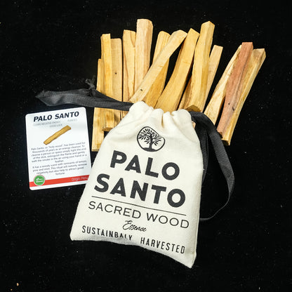 Palo santo incense sticks with their cotton drawstring pouch and information card on a black surface