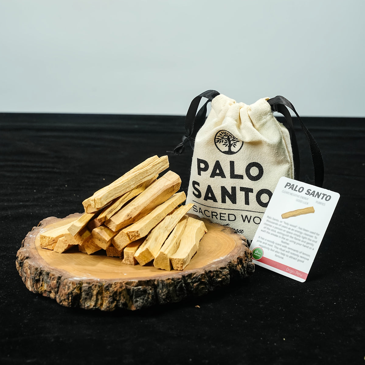Palo santo sticks arranged on a wood slice with the drawstring pouch behind
