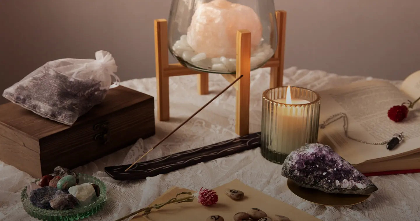 Tabletop setting with incense, candles, and crystals on a white cloth