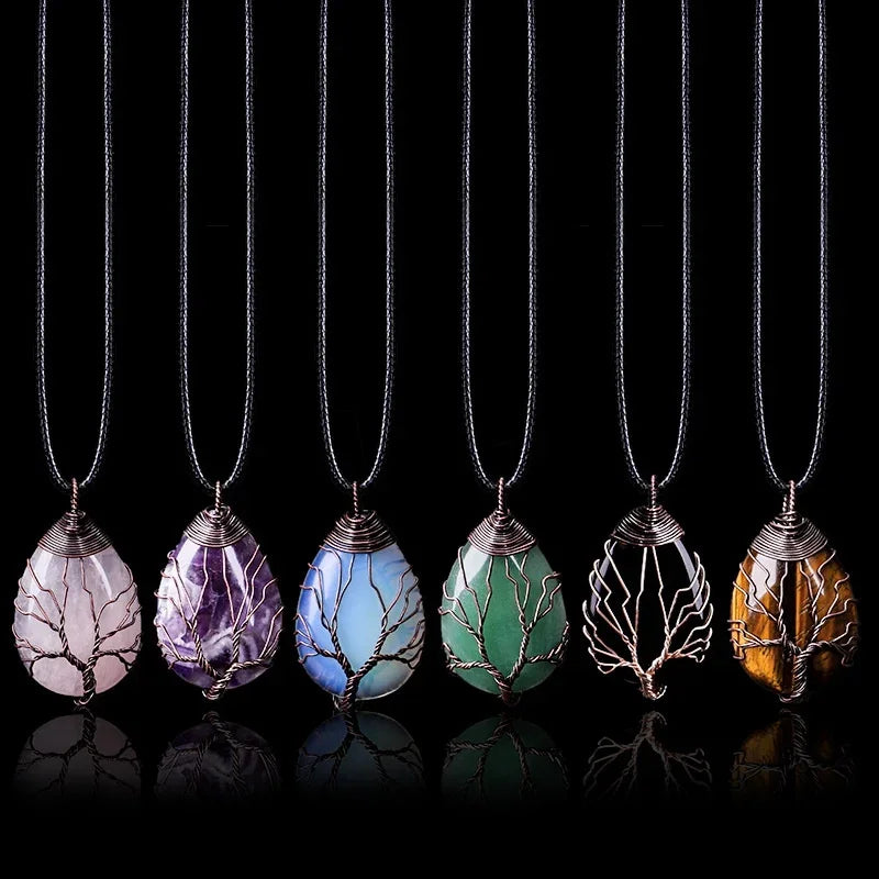 Six Tree of Life pendant necklaces side by side, each a teardrop gemstone wrapped in a wire tree - rose quartz, amethyst, blue stone, green aventurine, clear quartz and tiger eye