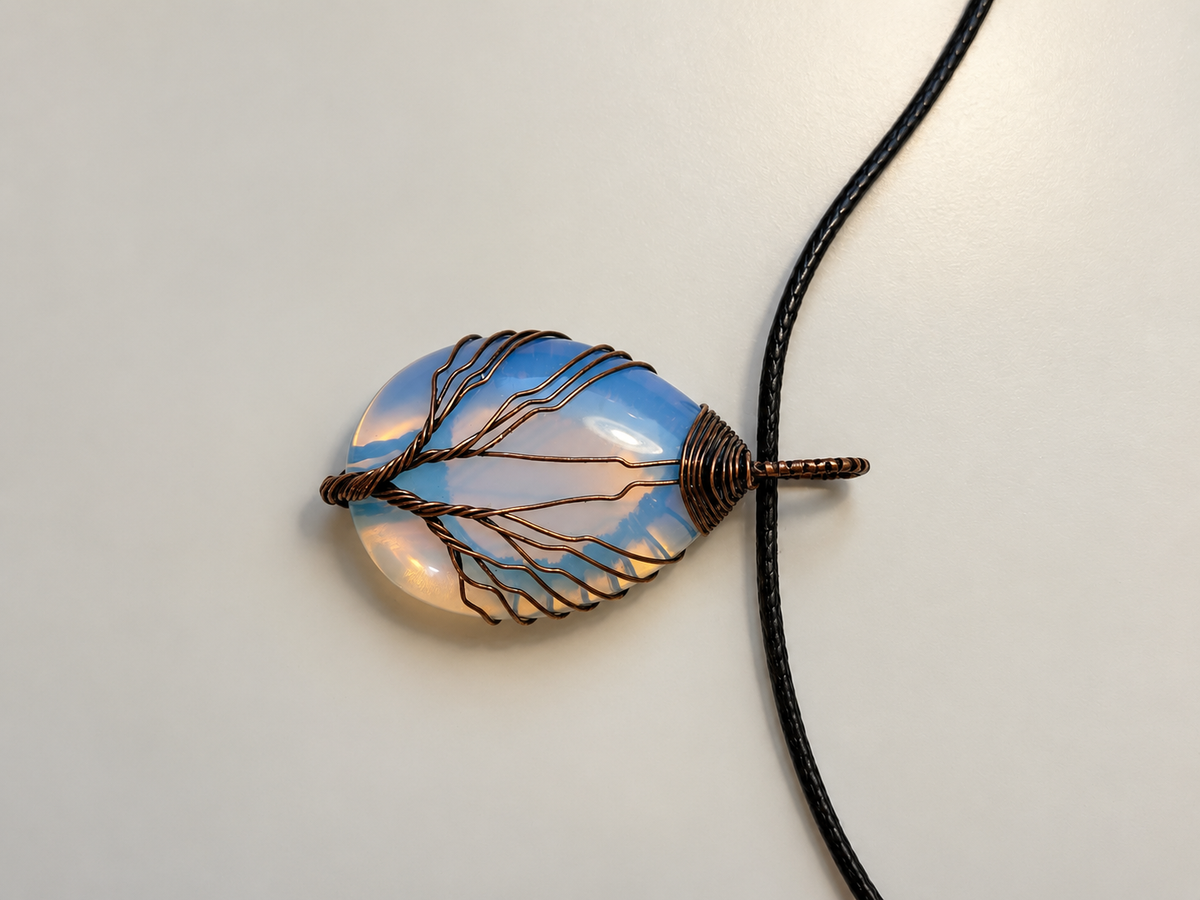 Opal teardrop stone wrapped in a wire Tree of Life, iridescent in the light